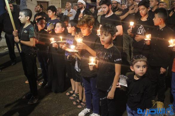 بالصور:موكب جمعية التضامن الاسلامي يحيي ليلة الحادي عشر من المحرم بمسيرة من الشموع